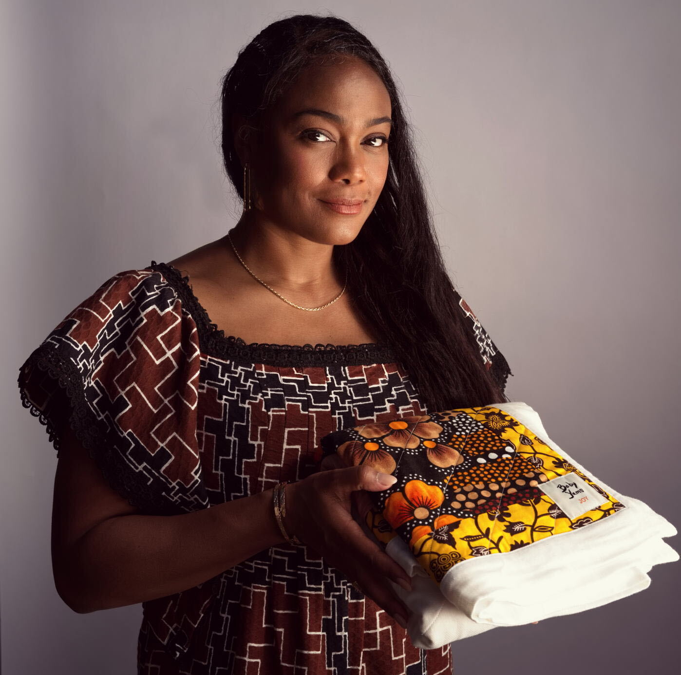Actor Tatyana Ali holds a Baby Yams quilt. Ali